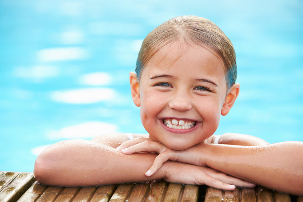 Una niña sonríe en una piscina en el período veraniego